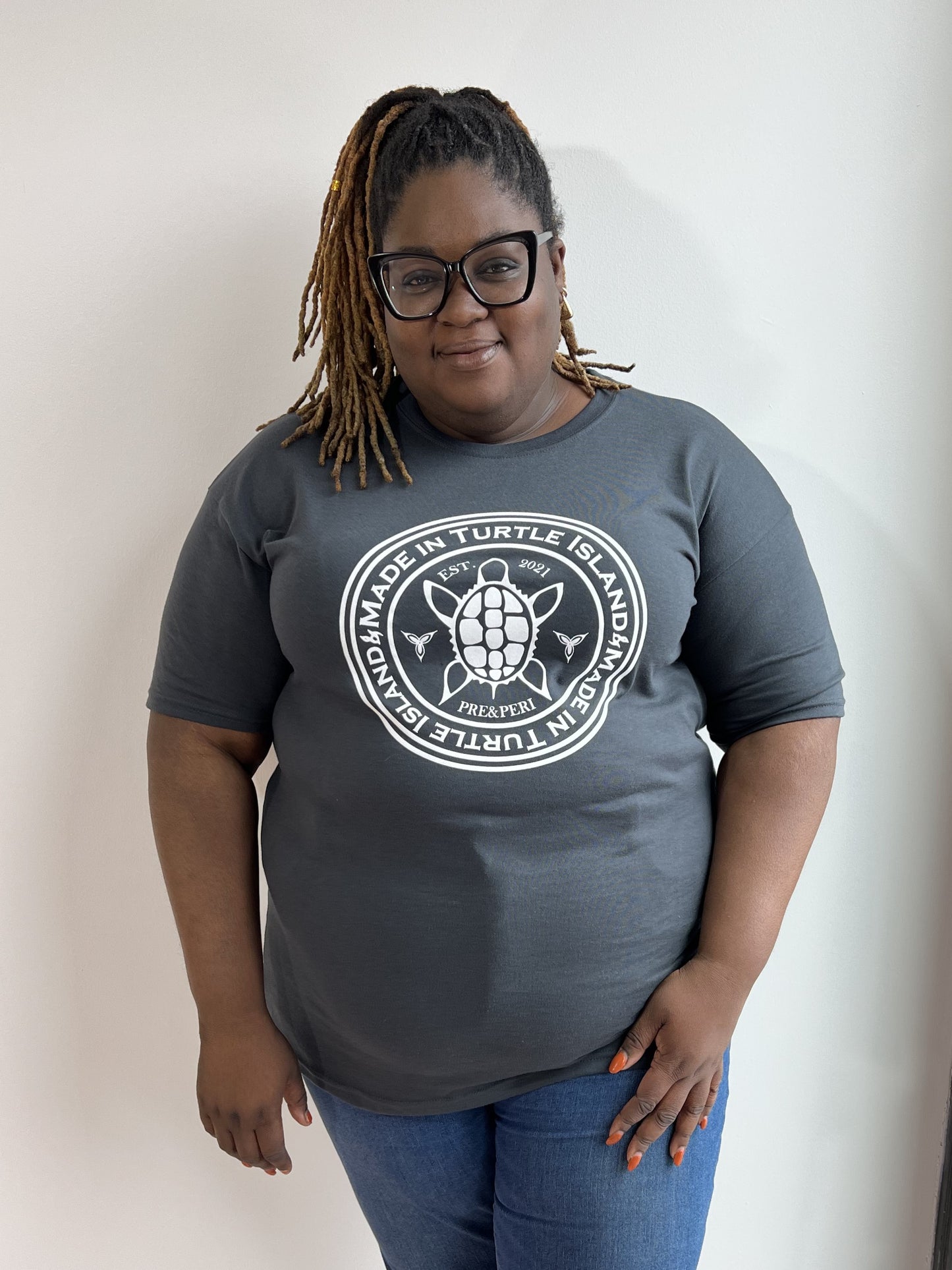A woman wearing a charcoal t-shirt with a white turtle print with the words "Made in Turtle Island" around it.