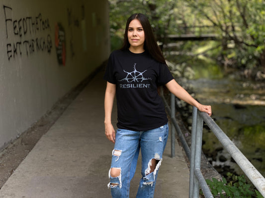 A woman wearing a black t-shirt with a stylized rising sun graphic above the word "Resilient"