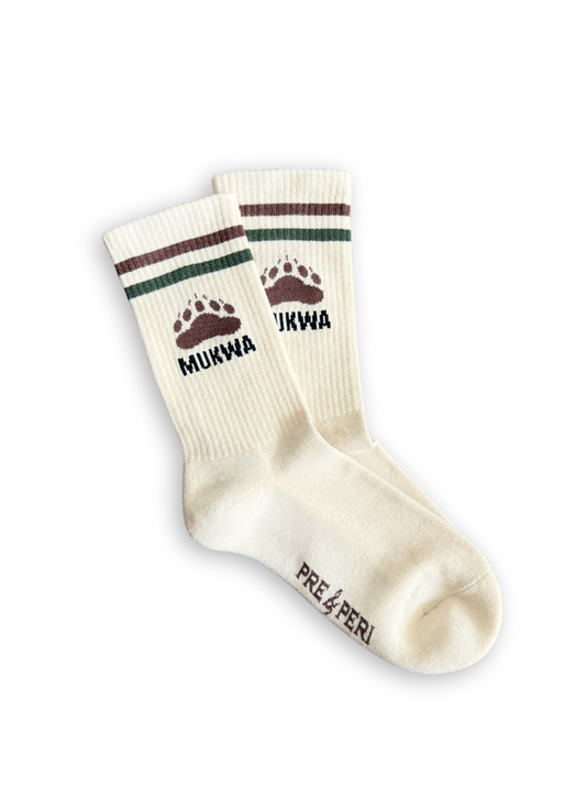 Pair of cream socks with brown and green accents and 'Mukwa' under a bear paw print.