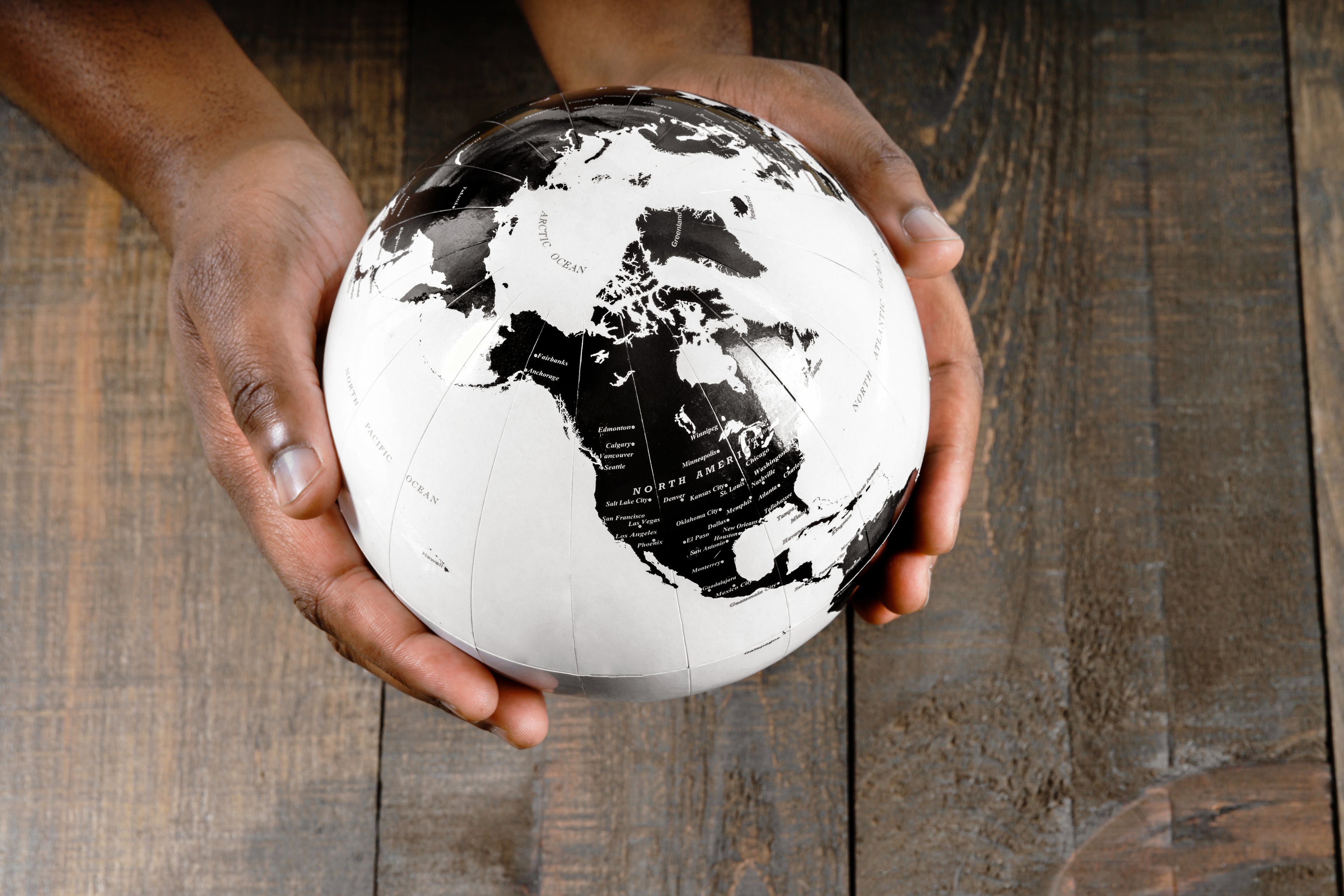 2 hands holding a black and white globe focused on North America or Turtle Island