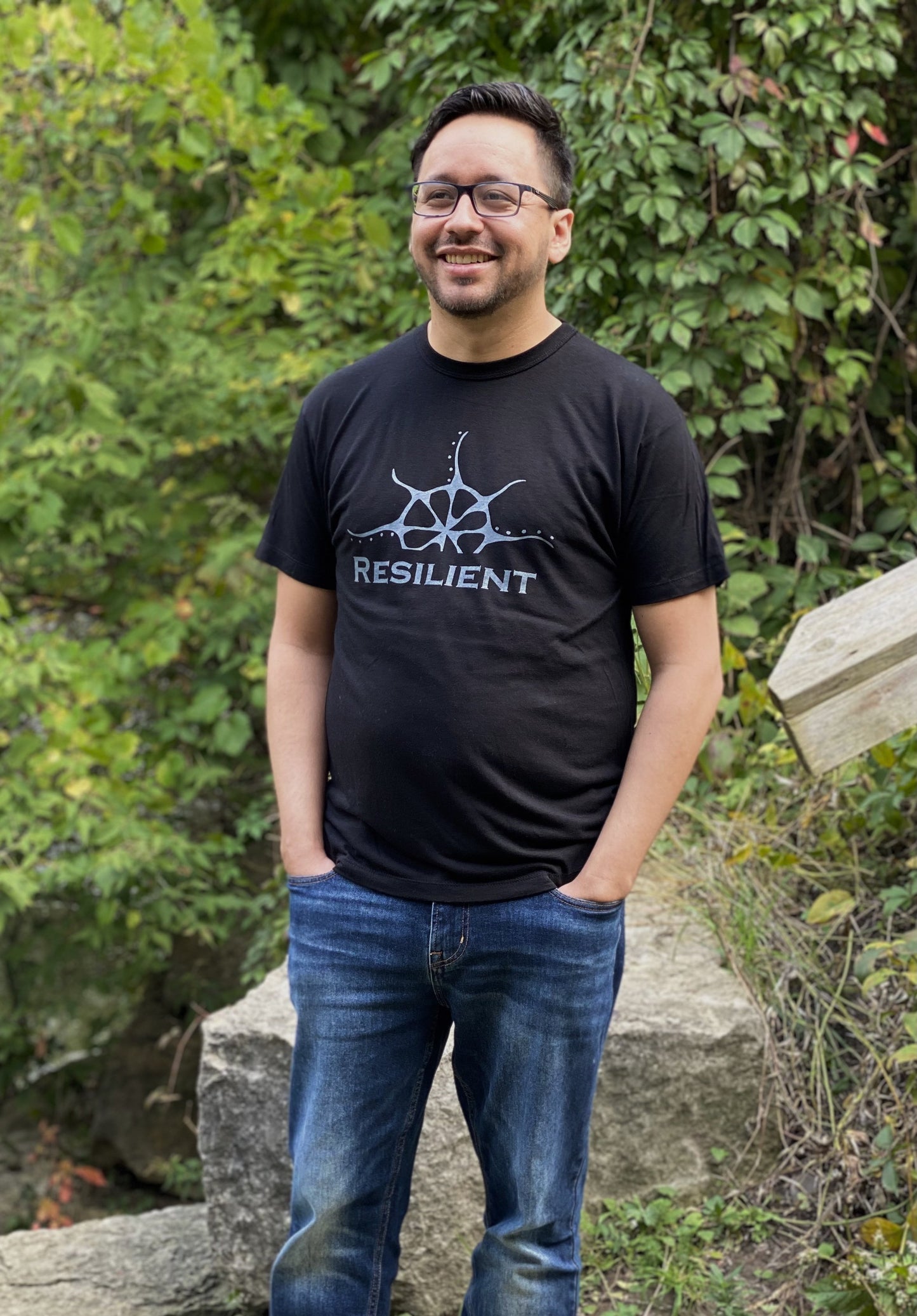 Black bamboo unisex t-shirt on a man with a stylized rising sun graphic above the word "Reslilient"