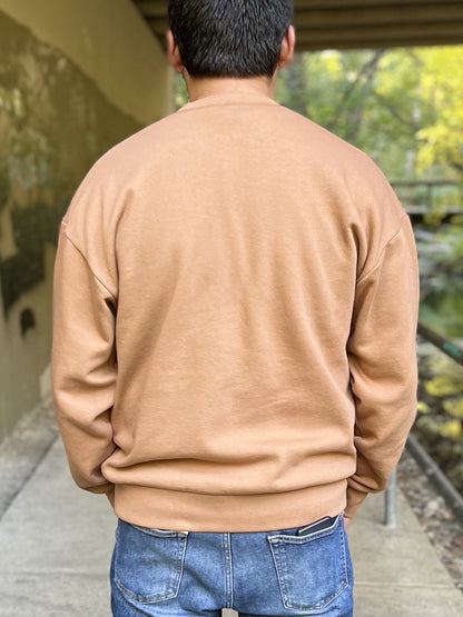 The back of a camel-coloured crewneck sweatshirt on a man