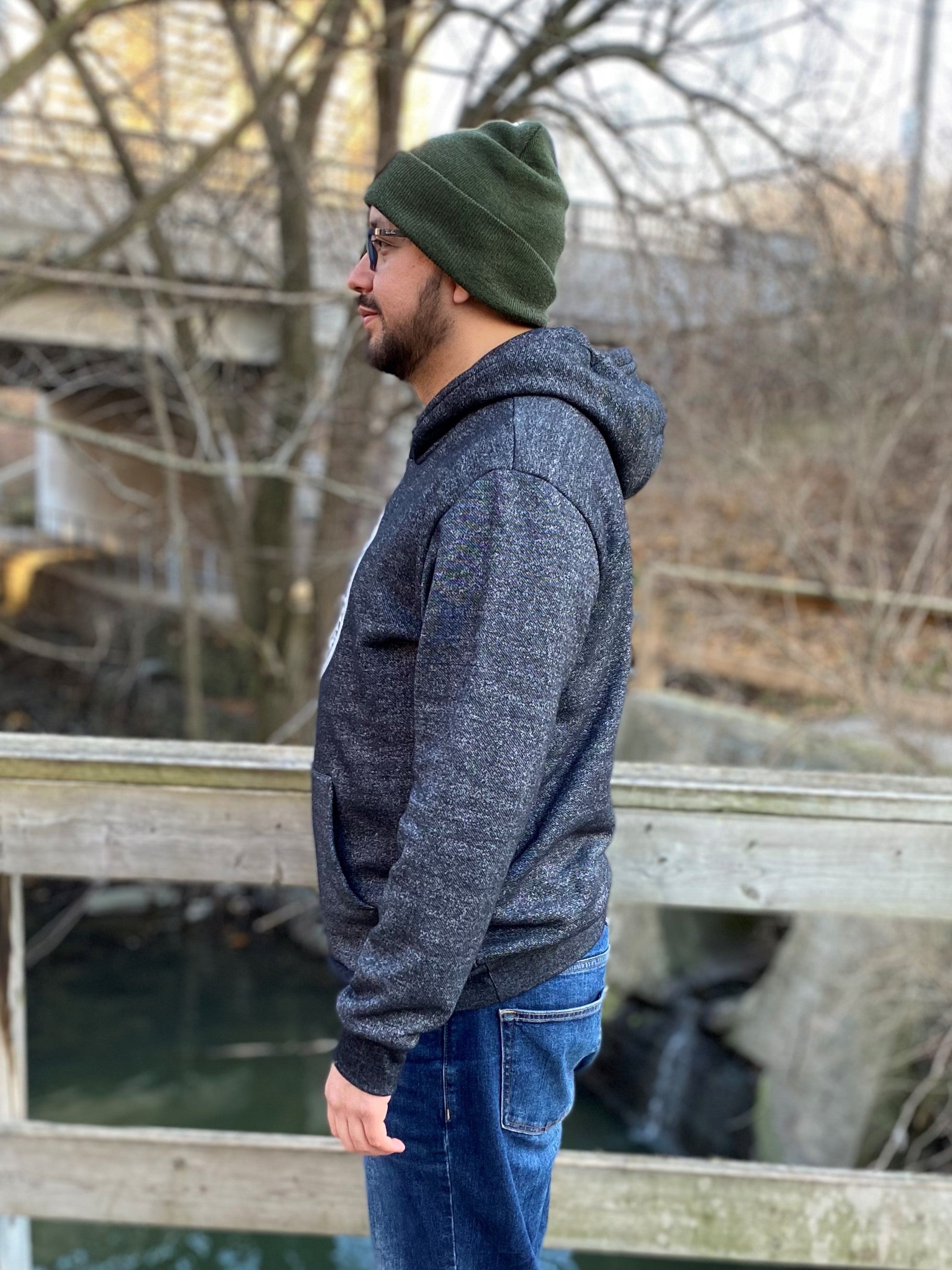 Side view of a bearded man wearing a green toque and salt and pepper hoodie