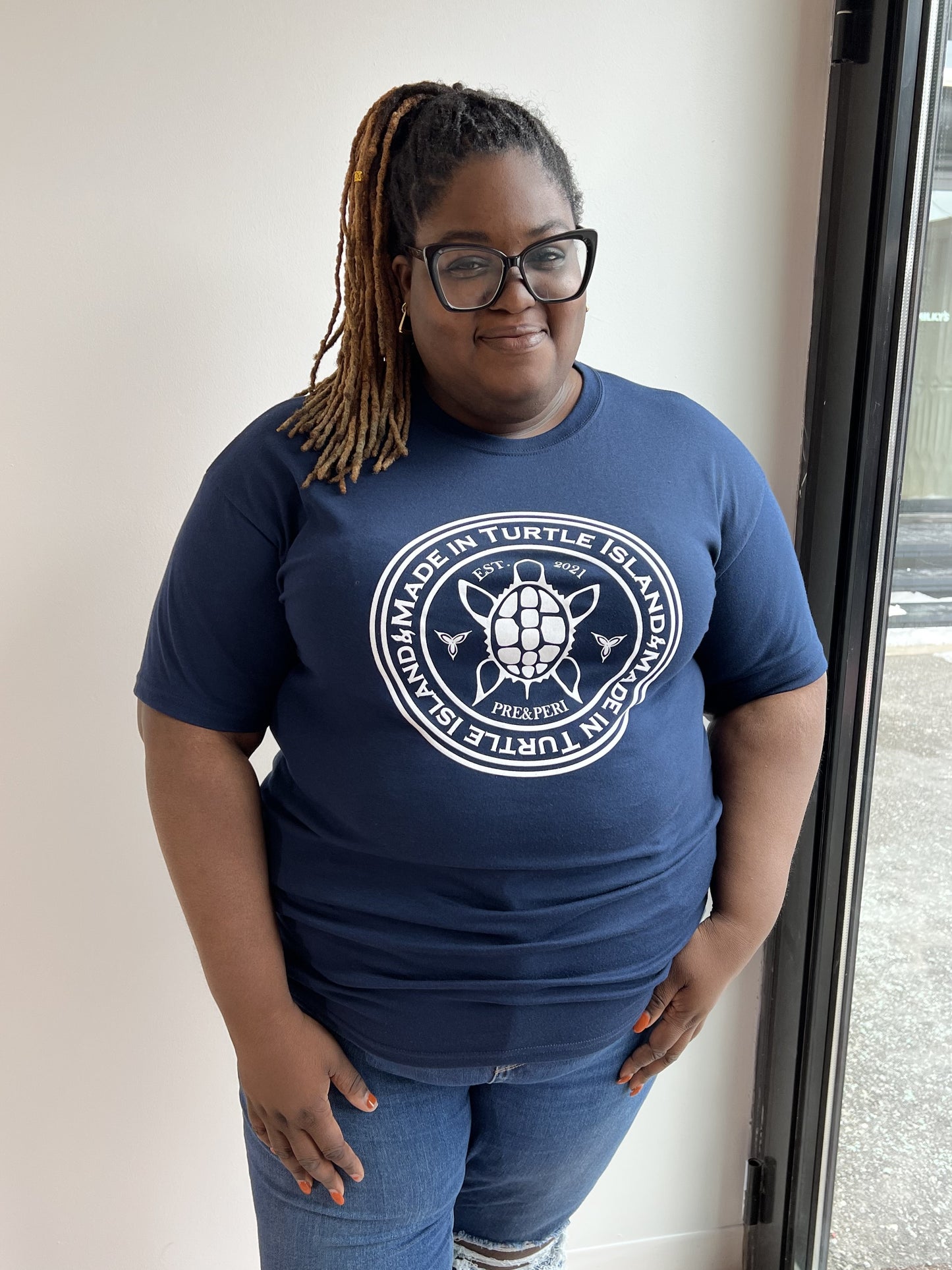 A woman wearing a navy t-shirt with a white turtle print with the words "Made in Turtle Island" around it.