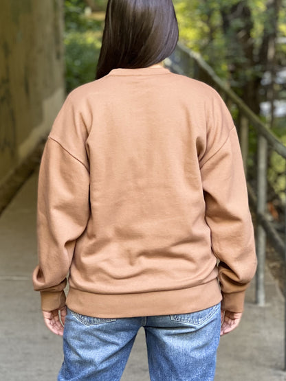 The back of a camel-coloured crewneck sweatshirt on a woman