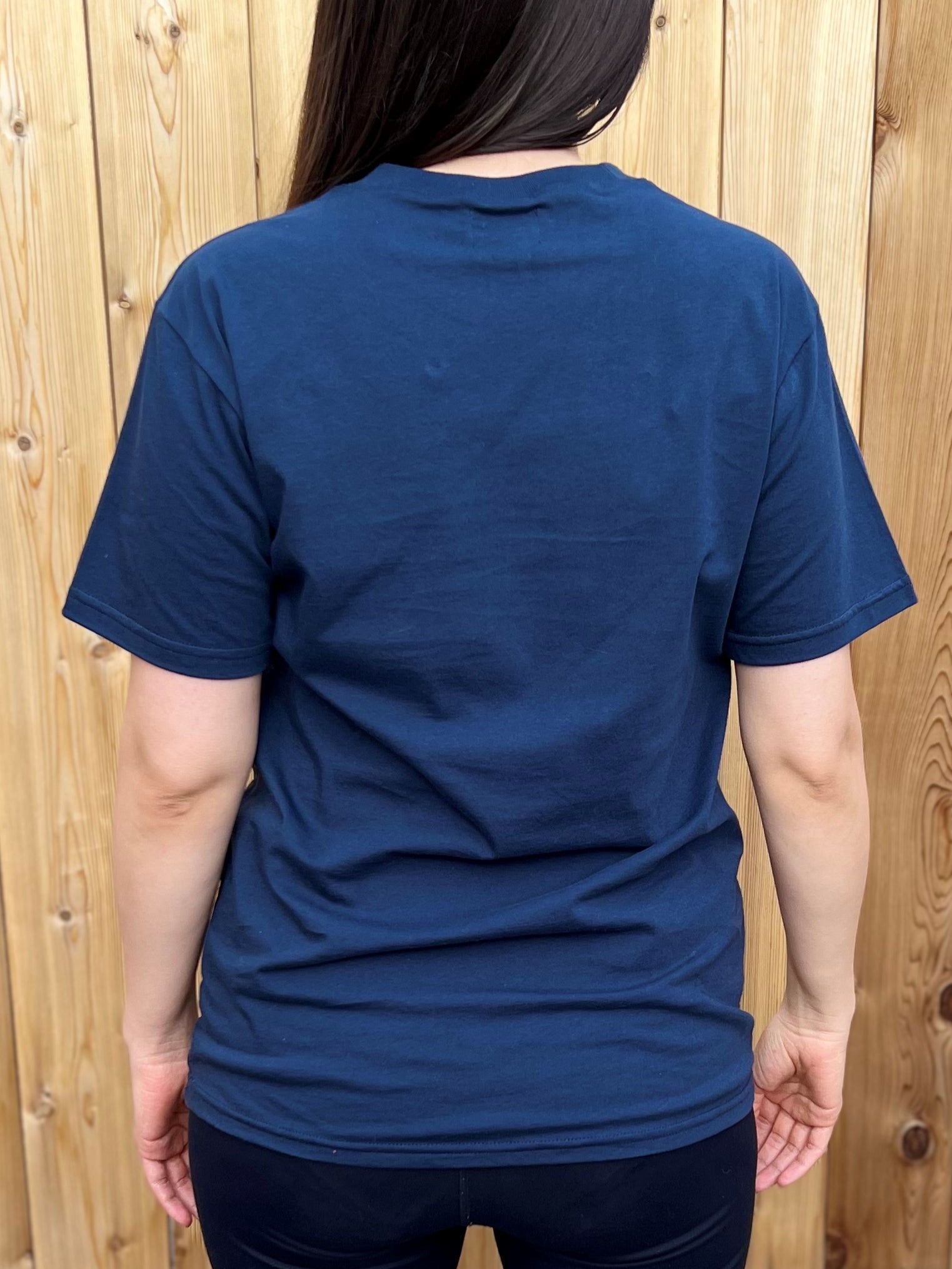 The back of a navy t-shirt worn by a woman.